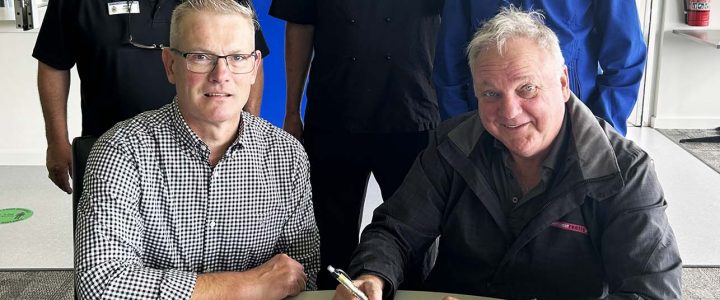 Group of five men at a table signing an agreement for the catering for the Victor Harbor Roos Club.